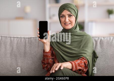Senior Middle-Eastern Female Showing Phone With Empty Screen At Home Stock Photo