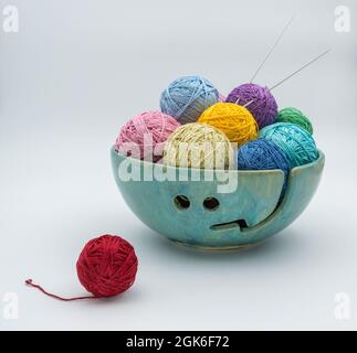 Skeins of yarn and knitting needles in a ceramic bowl. Stock Photo