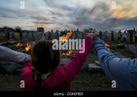 ZAPORIZHZHIA REGION, UKRAINE - SEPTEMBER 11, 2021 - People hold hands as they reel dance around the bonfires placed among the boulders in the Scythian Stock Photo