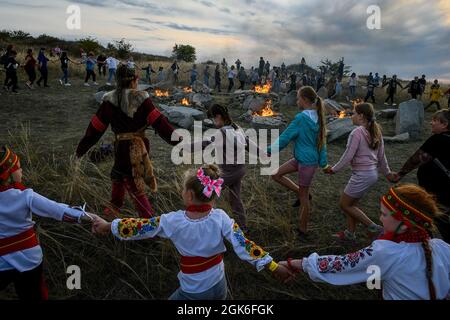 ZAPORIZHZHIA REGION, UKRAINE - SEPTEMBER 11, 2021 - Children reel dance around the bonfires placed among the boulders in the Scythian Camp Park of Meg Stock Photo