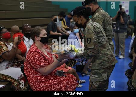 A bouquet of yellow roses are being presented to Maj. Rodney T. Hayward the 926th Preventative Medicine Detachment commander’s spouse, Mrs. Maggie Hayward and a single rose to each of his children Slade, Elloise and Kane during the 14th Field Hospital activation and assumption to command ceremony to welcome them to the 14th Field Hospital family at Newman Gym on Fort Stewart, Georgia, Aug 17. The flowers signify the warm relationship that exists within the command that will grow during their time with the 14th Field Hospital. Stock Photo