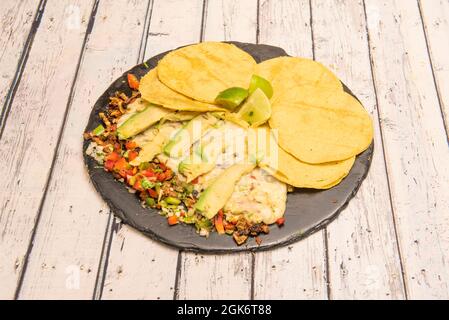 Combined Mexican dish of beef wire with slices of avocado, sautéed vegetables, small corn tortillas and pieces of lime Stock Photo
