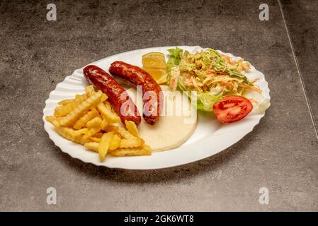 Venezuelan arepa breakfast with fried sausages, coleslaw and chips on gray background Stock Photo