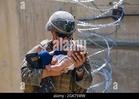 210821-M-JM820-1025 HAMID KARZAI INTERNATIONAL AIRPORT, Afghanistan (August 21, 2021) – A U.S. Marine assigned to 24th Marine Expeditionary Unit (MEU) comforts an infant while they wait for the mother during an evacuation at Hamid Karzai International Airport, Kabul, Afghanistan, Aug. 21. U.S. service members are assisting the Department of State with a Non-combatant Evacuation Operation (NEO) in Afghanistan.