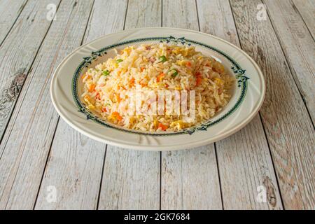 Three delicious rice dishes typical of a Chinese restaurant with fried egg filaments, carrot pieces, ham and peas on a white table Stock Photo
