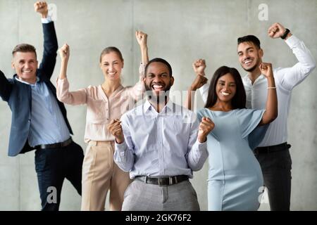 Successful Team. Group Of Multiracial Colleagues Celebrating Business Achievement With Raised Fists Stock Photo