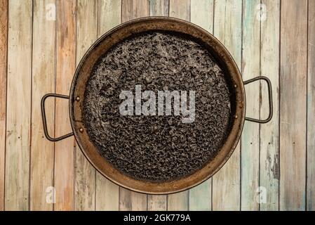 Spanish paella of delicious rice dyed black with squid ink on wooden table Stock Photo