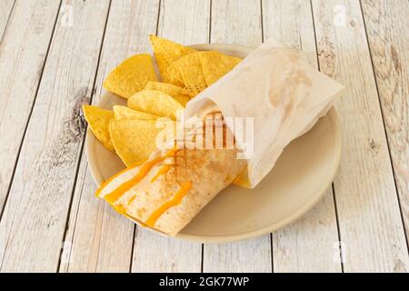 Wrap filled with bacon, a sausage and cheddar cheese garnished with corn nachos Stock Photo