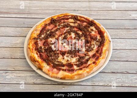 BBQ pizza with lots of bacon and minced meat with lots of sauce and mozzarella cheese on white plate Stock Photo