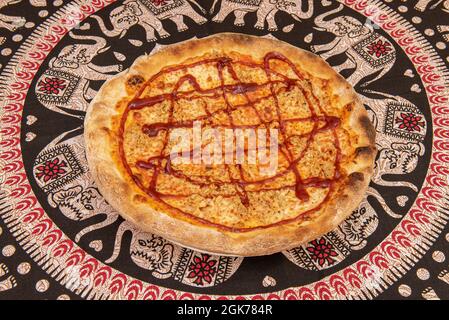 Pizza with stewed minced meat, mozzarella cheese and  barbecue sauce with wheat flour dough on a tablecloth with Asian elephants Stock Photo