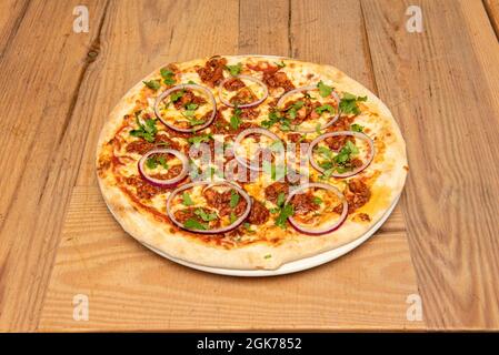 Great BBQ pizza with raw red onion rings and lots of parsley. Minced meat with tomato and baked wheat flour dough Stock Photo