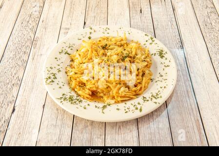 Portuguese style dourada cod with lots of parsley and straw potatoes on white wooden table Stock Photo