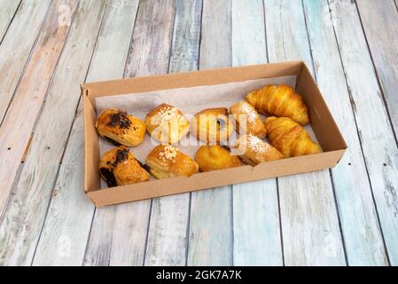 Assorted pastries of chocolate, cream and butter inside a cardboard container. Neapolitans, conches, croissants and angel hair Stock Photo