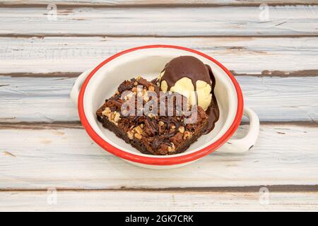 Piece of chocolate brownie with nuts with vanilla ice cream and chocolate syrup. Stock Photo