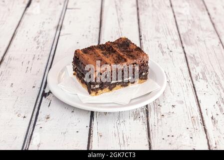Portion of oreo brownie cake on white napkins on a white plate and on a white table in turn Stock Photo