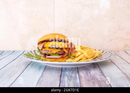 Beef burger with double meat, melted cheddar cheese and slices of fried bacon and white onion Stock Photo