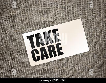 words Take care on card on burlap canvas. healthcare or business concept Stock Photo