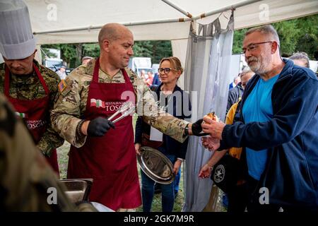 U.S. Army Lt. Col. Craig Broyles, commander of Battle Group Poland, hands a fish burger to a local citizen during the Days of Orzsyz festival in Orzysz, Poland, August 27, 2021. Battle Group Poland's leaders joined the local community to celebrate the Days of Orzysz, strengthening our partnership. Stock Photo