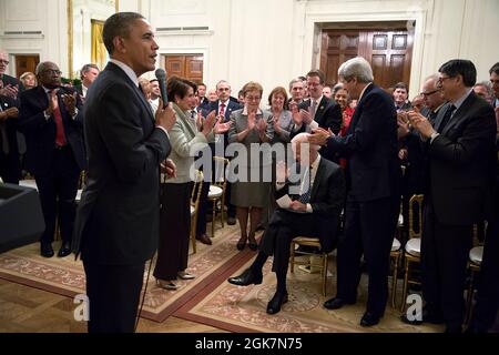 President Barack Obama looks on as attendees applaud Vice President Joe Biden during a meeting with the House Democratic Caucus in the East Room of the White House, Feb. 4, 2014. (Official White House Photo by Pete Souza) This official White House photograph is being made available only for publication by news organizations and/or for personal use printing by the subject(s) of the photograph. The photograph may not be manipulated in any way and may not be used in commercial or political materials, advertisements, emails, products, promotions that in any way suggests approval or endorsement of Stock Photo