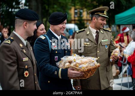 From left, Croatian Land Forces Capt. Dario Biljeskovic, commander of Storm Battery, U.S. Army Lt. Col. Craig Broyles, commander of Battle Group Poland, and Romanian Land Forces Maj. Mircea Zemtev, commander of Sky Guardians, hand out bread to Orzysz citizens during the Harvest Festival in Orzysz, Poland, August 29, 2021. Battle Group Poland's leaders joined the local community to celebrate the Days of Orzysz and the Harvest Festival, strengthening our partnership. Stock Photo