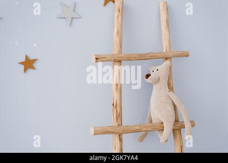 Soft toy bear sits on a wooden staircase in the decor of the children's room Stock Photo