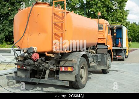 Machines with a water tank. Water filling machine in the city. Washing vehicles in the park. City cleaning service of the city. Stock Photo