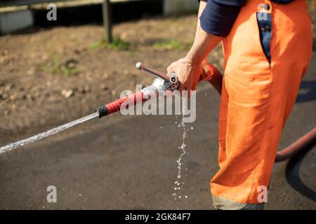 Water hose. The flow of water from the pipe. A man holds a fire hose. Stock Photo