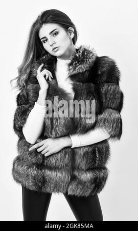 Fur store model posing in soft fluffy warm coat. Pretty fashionista. Fur fashion concept. Woman makeup and hairstyle posing mink or sable fur coat Stock Photo