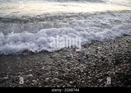 Sea foam on the gravel shore Stock Photo