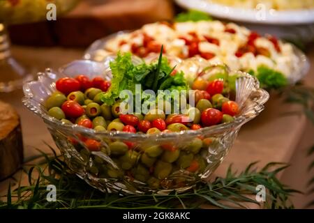 Salada de azeitonas, tomates e alface em mesa de buffet com vários pratos diferentes. Stock Photo