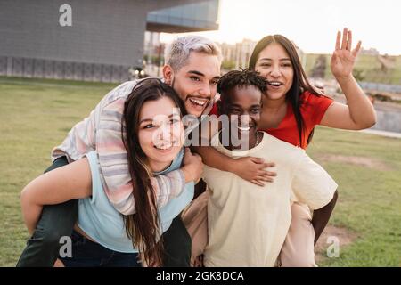 Young diverse people having fun together outdoor at city park - Focus on left girl face Stock Photo