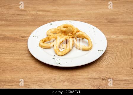Tapa of squid rings battered in flour and egg cooked Andalusian style on a round white plate Stock Photo