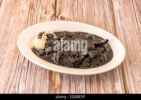 Spanish recipe tray of squid in its ink with white rice garnish and lots of sauce covering the squid Stock Photo