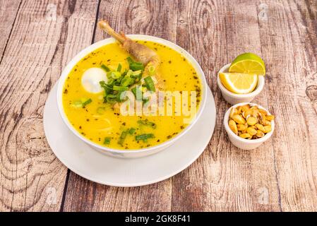 Old chicken broth with typical Peruvian recipe accompanied by a bit of cancha and slices of lime and lemon on wooden table Stock Photo