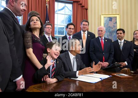 Mark and Ellyn Miller and their son Jacob react before President Barack Obama signs H.R. 2019, the Gabriella Miller Kids First Research Act, in the Oval Office, April 3, 2014. The law ends taxpayer contributions to the Presidential Election Campaign Fund and diverts the money in that fund to pay for research into pediatric cancer through the National Institutes of Health (NIH). (Official White House Photo by Pete Souza) This official White House photograph is being made available only for publication by news organizations and/or for personal use printing by the subject(s) of the photograph. Th Stock Photo