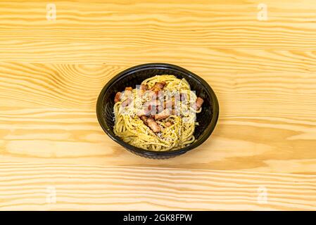 Fresh pasta spaghetti cooked with carbonara sauce and many fried bacon tacos on pine wood table Stock Photo