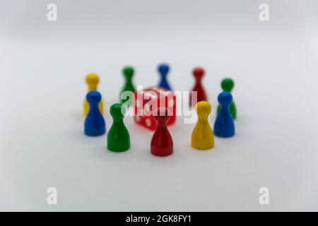 Different colours and shapes of pawn pieces and dices from board games, on a wooden background. Stock Photo
