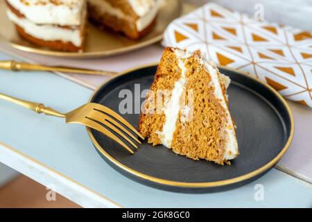 Portion of carrot cake with sweet frosty, pieces of nuts and golden cutlery Stock Photo