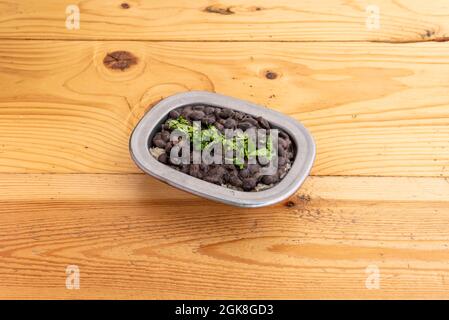 Caribbean rice with black beans served in small stainless steel bowl on pine wood table Stock Photo