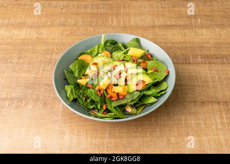 Vegan salad of spinach, avocado, chopped pineapple, nuts and peach chunks Stock Photo