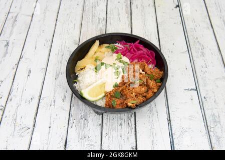 bowl of Mexican cochinita pibil with fried yucca and white rice. Shredded chicken, lime and coriander stew with preserved purple onion. Stock Photo