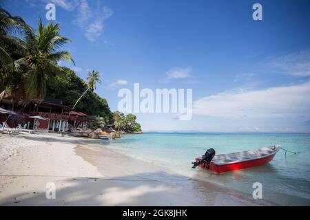 Boat on clear azure sea rolling on wet sandy beach in Malaysia Stock Photo