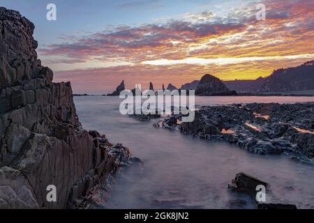 Spectacular scenery with foamy sea waves washing rough rocky formations of various shapes on wild beach of Geirua in Asturias Spain during sunset Stock Photo