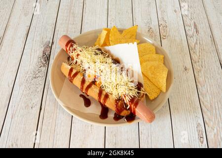 Hot dog with Mexican chili sauce, cheddar cheese and shredded cheese garnished with corn chips Stock Photo