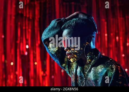 Trendy young black female in cyberpunk glasses with shadows on face in light beams in nightclub Stock Photo