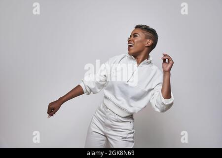 Energetic ethnic Woman in trendy clothes dancing hip hop with open mouth and eyes closed Stock Photo