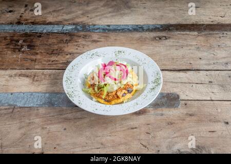 Delicious large Mexican taco with corn tortilla with recipe for cochinita pibil with purple onion on beautiful wooden table Stock Photo