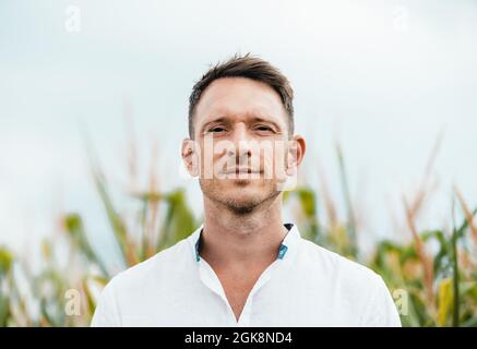 Adult bearded male with brown hair in casual wear looking at camera under light sky Stock Photo