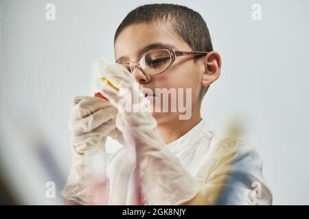 Portrait of a schoolboy in white fully concentrated on his homework Stock Photo