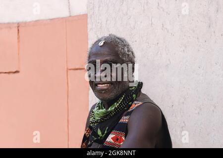 Cool middle aged African American male in modern sunglasses sitting on chair in daylight Stock Photo